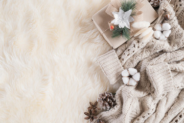 Autumn or winter composition. Gift box Coffee cup, cinnamon sticks, anise stars, beige sweater with knitted blanket on cream color gray fluffy background. Flat lay top view copy space.