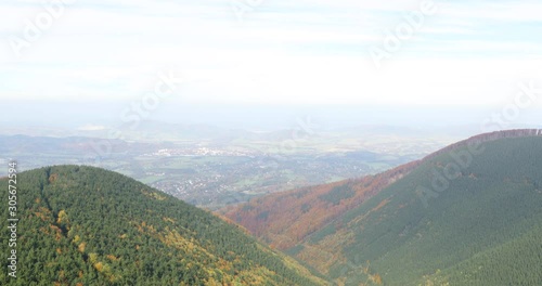 Hills and mountains on the horizon of beautiful nature with city in the forest valley view into vast distance of the Beskids Area during a windy sunny day captured in Radhost Pustevny area 4k 60fps. photo