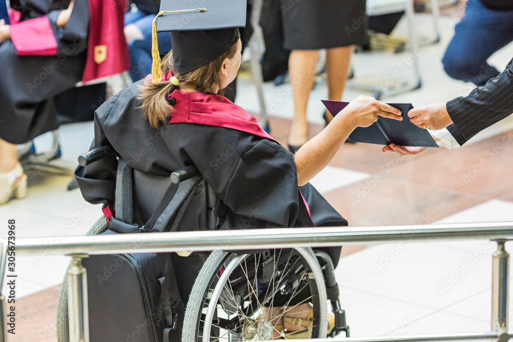 student in wheelchair receives a diploma from a university. disabled girl with a diploma from school and university. - obrazy, fototapety, plakaty 