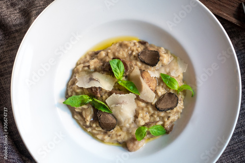 Risotto with mushrooms, Parmesan cheese, Basil and truffle on a white plate, Italian dish, top view