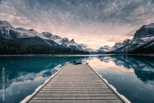 Traveler relaxing on wooden pier in Maligne lake at Spirit island, Jasper national park