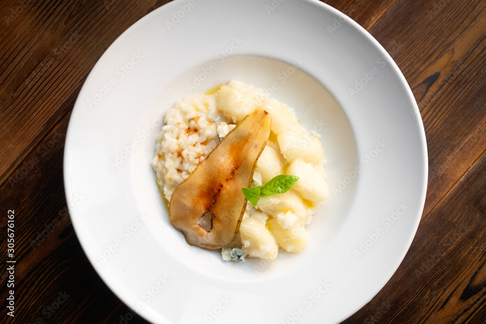 Risotto with pear and Gorgonzola on a white plate. Italian dishes are served in the restaurant Risotto with pear and Gorgonzola on a white plate. Italian dishes are served in the restaurant