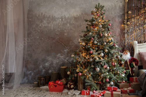 close up photo of a decorated Christmas tree near a white bed with pillows on it photo