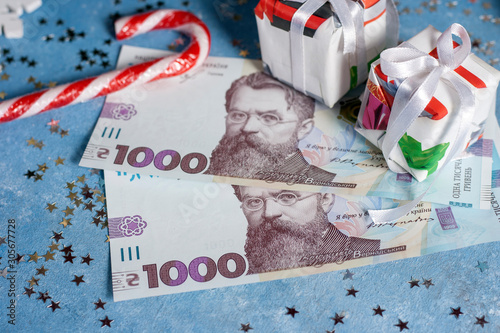 Ukrainian 1000 hryvnia on a blue background with stars, candy and gifts. The concept of buying Christmas and New Year gifts in Ukraine