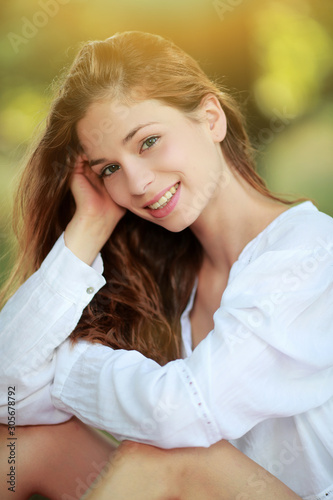 Jolie jeune femme assise sous un arbre souriante