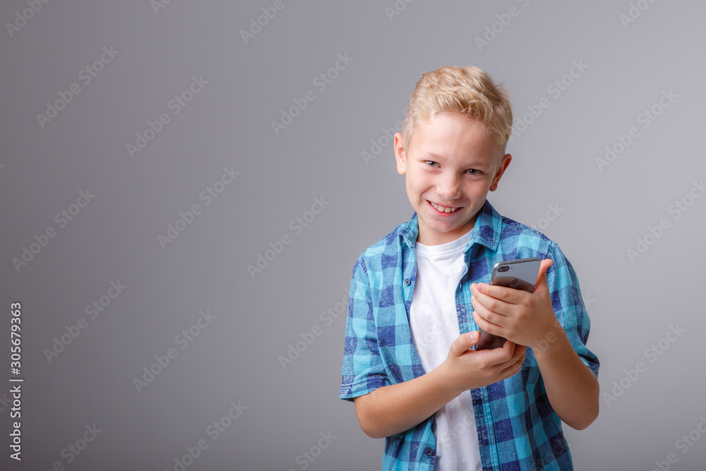 portrait of a boy talking on a mobile phone isolated on a gray background portrait of a boy talking on a mobile phone isolated on a gray background