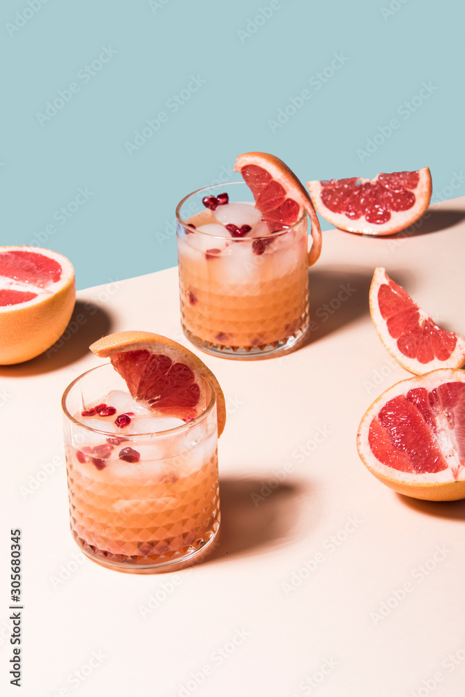 Fresh summer cocktail with pink grapefruit slices. Divided blue and beige bankground. Abstract conception. Fresh summer cocktail with pink grapefruit slices. Divided blue and beige bankground. Abstract conception.