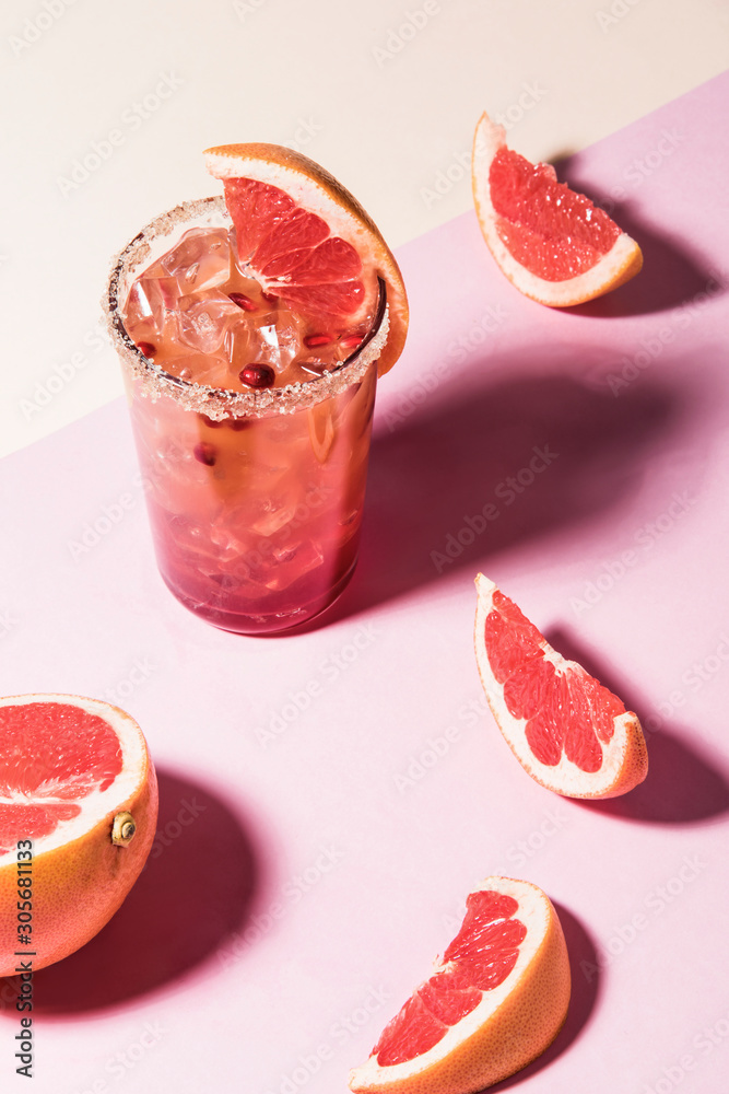 Fresh summer cocktail with pink grapefruit slices. Divided pink and beige bankground. Abstract conception. Fresh summer cocktail with pink grapefruit slices. Divided pink and beige bankground. Abstract conception.