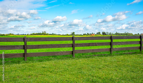 Green fence field and a blue sky. Pastures out of town.