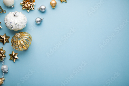 Merry Christmas and Happy Holidays greeting card, frame, banner. New Year. Noel. Christmas white and golden ornaments on blue background top view. Winter xmas holiday theme