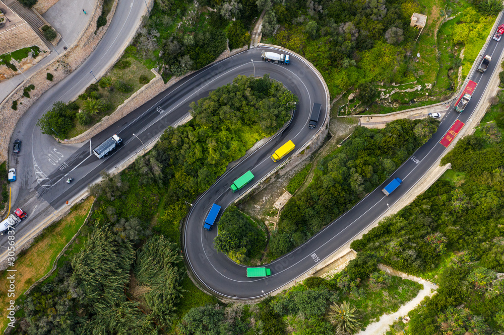 Colorful trucks on the curves road in Mellieha city. Top view. Malta island