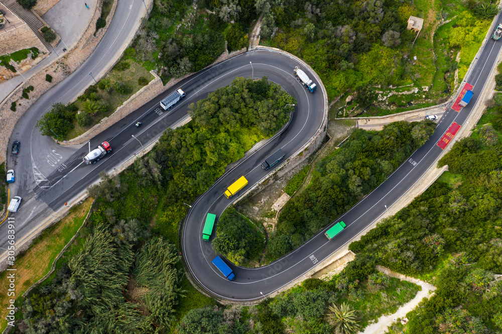 Colorful trucks on the curves road in Mellieha city. Top aerial view. Malta 