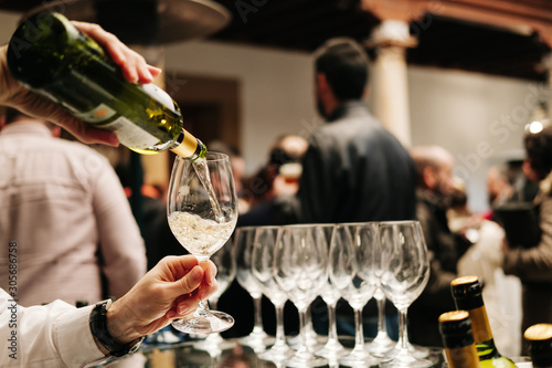 Bild auf Leinwand A waiter pours wine from a bottle into a glass at an event, meeting, wedding or