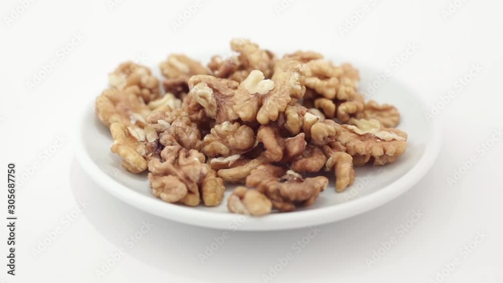 Walnuts spilling on a rotating plate on a white background Walnuts spilling on a rotating plate on a white background