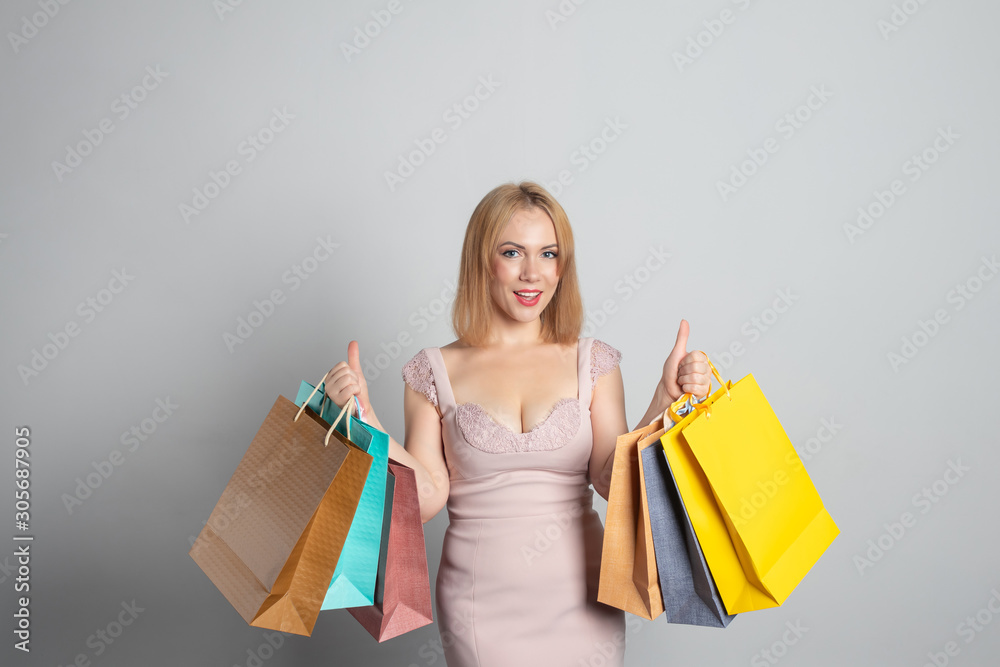 Girl with shopping bags on grey background
