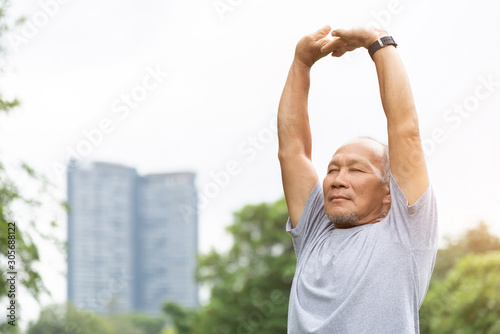 Fotografiet Asian senior man stretching his arms in the air before exercising