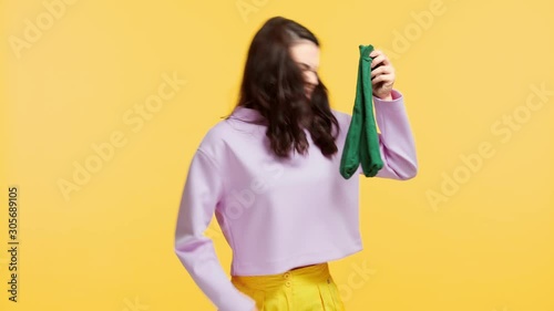 girl smelling stinky socks isolated on yellow