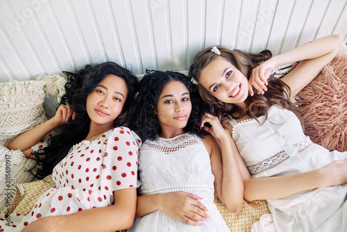 Beautiful multi ethnic girls relax together and lying on bed inside the camper van