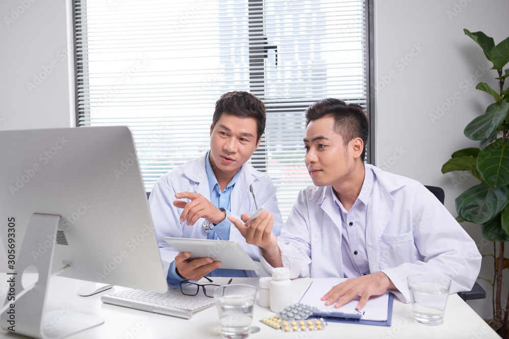 Two doctors holding and talking about patient on office Two doctors holding and talking about patient on office