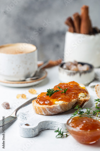 Closeup of pieces of white bread with apricot jam on light background