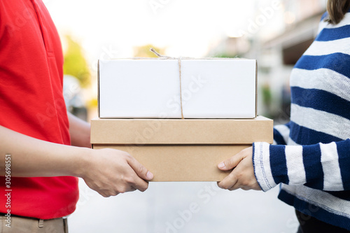 parcel delivery man of a package through a service. and close up hand customer female accepting a delivery of boxes from delivery man postal send direct to home.