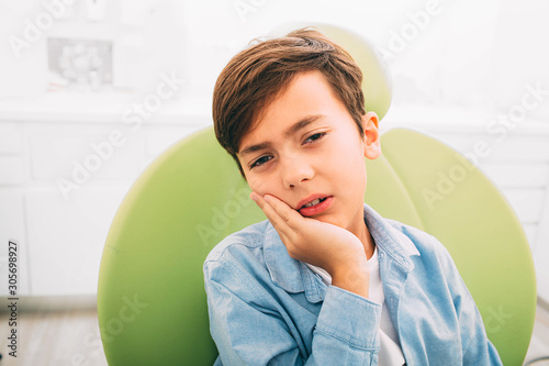 little boy with teeth pain, he is sad and upset.He setting and dentist chair ad dental clinic