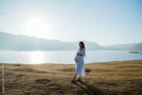pregnant mother holding her stomach enjoy sunrise