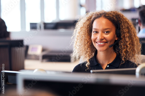 Portrait Of Young Businessman Wearing Telephone Headset Working In Customer Services Department