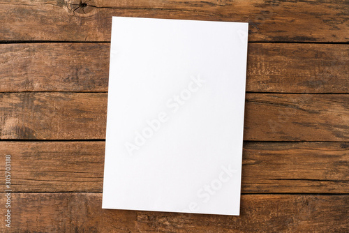 Empty white paper sheet on rustic wooden table. Top view photo