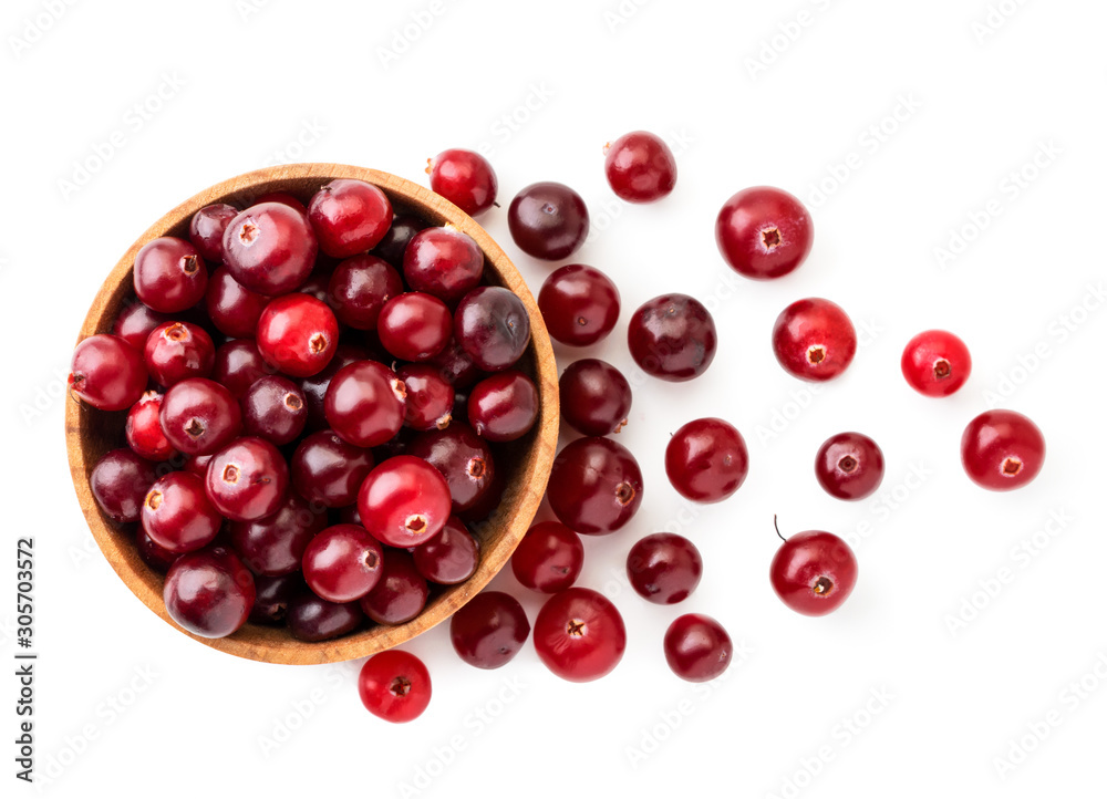Cranberries in a wooden plate and scattered on a white background. The view of top. Cranberries in a wooden plate and scattered on a white background. The view of top.