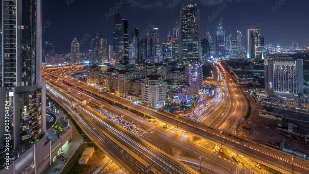 Skyline view of intersection traffic near Sheikh Zayed Road and DIFC day to night transition timelapse in Dubai, UAE. Illuminated skyscrapers in financial centre aerial view from above in downtown Skyline view of intersection traffic near Sheikh Zayed Road and DIFC day to night transition timelapse in Dubai, UAE. Illuminated skyscrapers in financial centre aerial view from above in downtown
