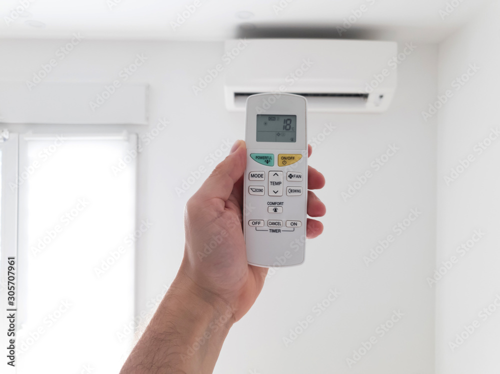 Modern airconditioner unit with a hand holding a remote. Modern airconditioner unit with a hand holding a remote.