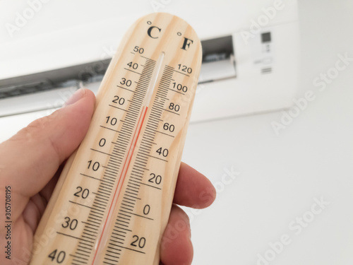 Foto Thermometer and temperature measuring with modern air condition unit on a white wall inside the living room