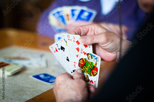 Elderly grandmother is playing cards. She is holding cards in her hand.