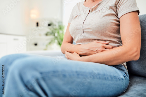 Woman with  stomach issues / problems while sitting on the couch.