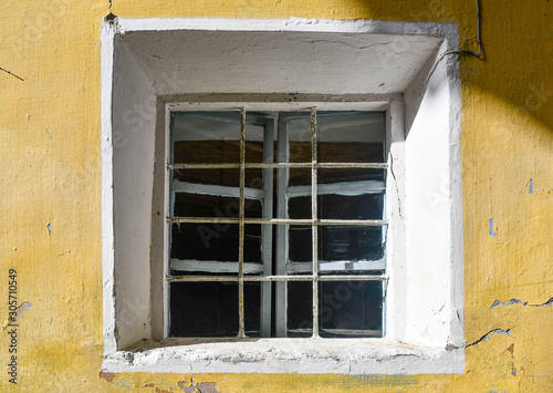 Close-up of the small  square window of an abandoned house with yellow wall background  Italy