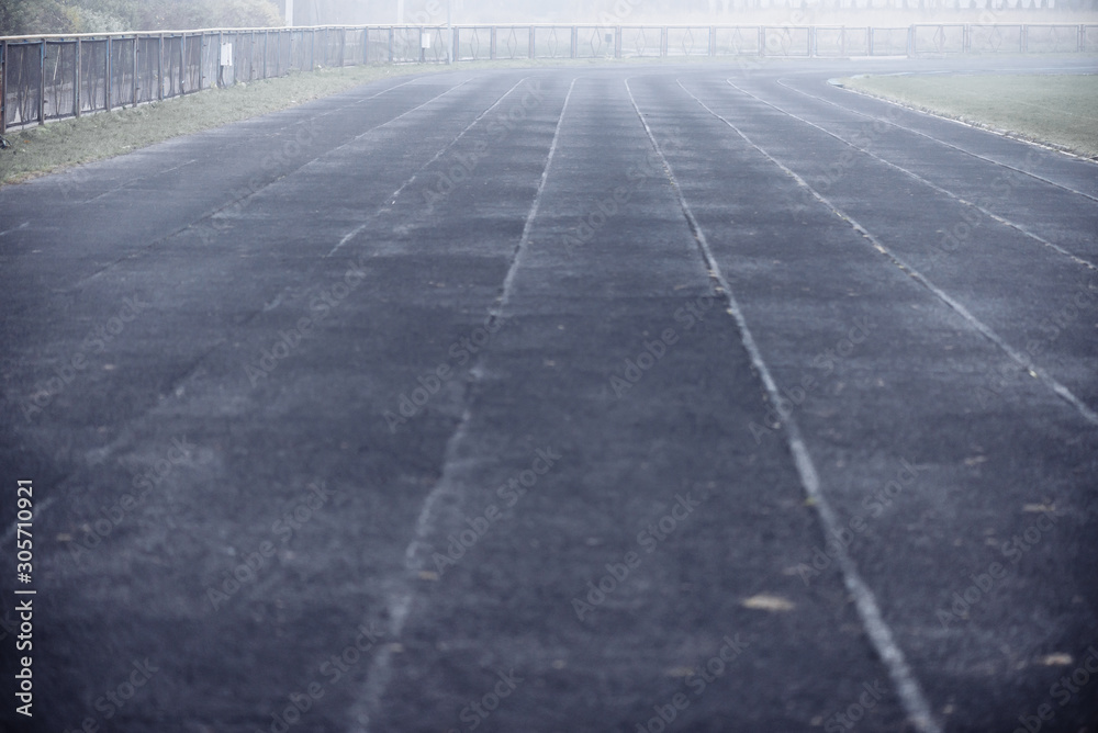 Running black rubber track at outdoor stadium in the fog