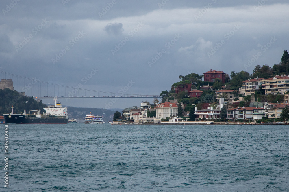 View of a dry cargo ship, Bosphorus, Asian side and some houses in a sunny cloudy day in Istanbul.