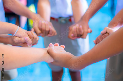 Children are standing, holding hands in a circle to play school activities.