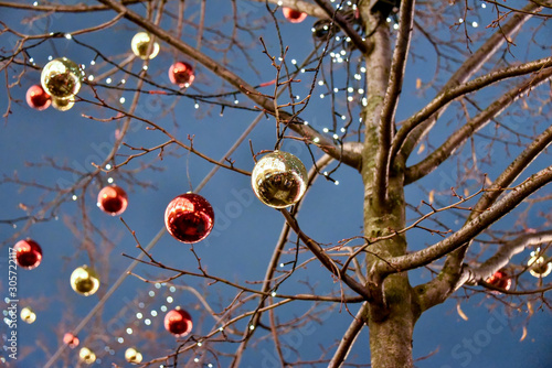 Tree decorated with Christmas balls with night lights as background