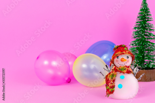 Snowman and colourful balloons on pink background