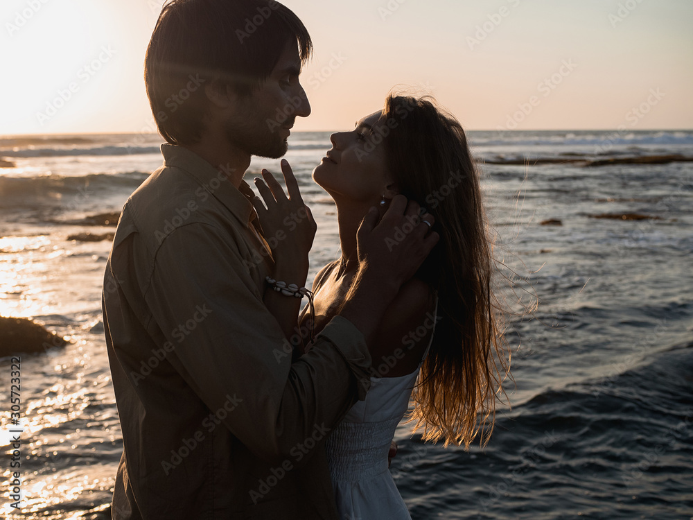 Attractive couple on vacation on the shore of the ocean at sunset time