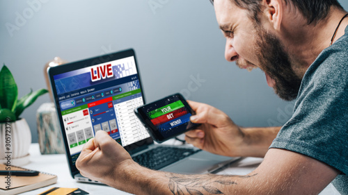 Fotografia Guy being happy winning a bet in online sport gambling application on his mobile