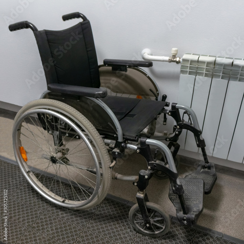 Folding wheelchair near the wall. Means of mobility of persons with disabilities