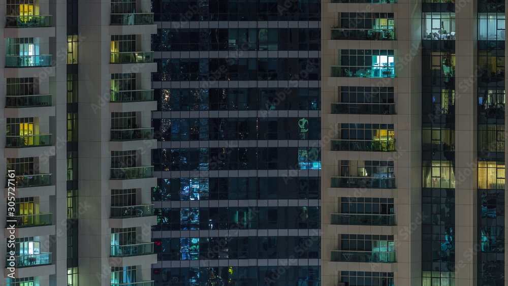 Rows of glowing windows with people in apartment building at night. Rows of glowing windows with people in apartment building at night.