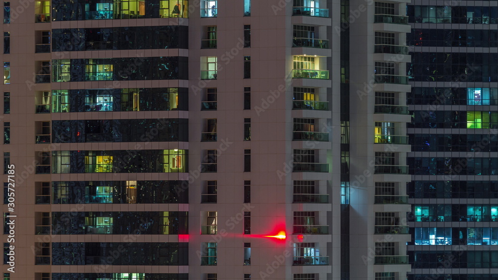Rows of glowing windows with people in apartment building at night. Rows of glowing windows with people in apartment building at night.