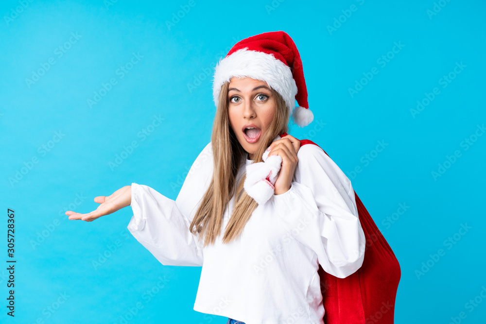 Young blonde woman picking up a bag full of presents over isolated background Young blonde woman picking up a bag full of presents over isolated background