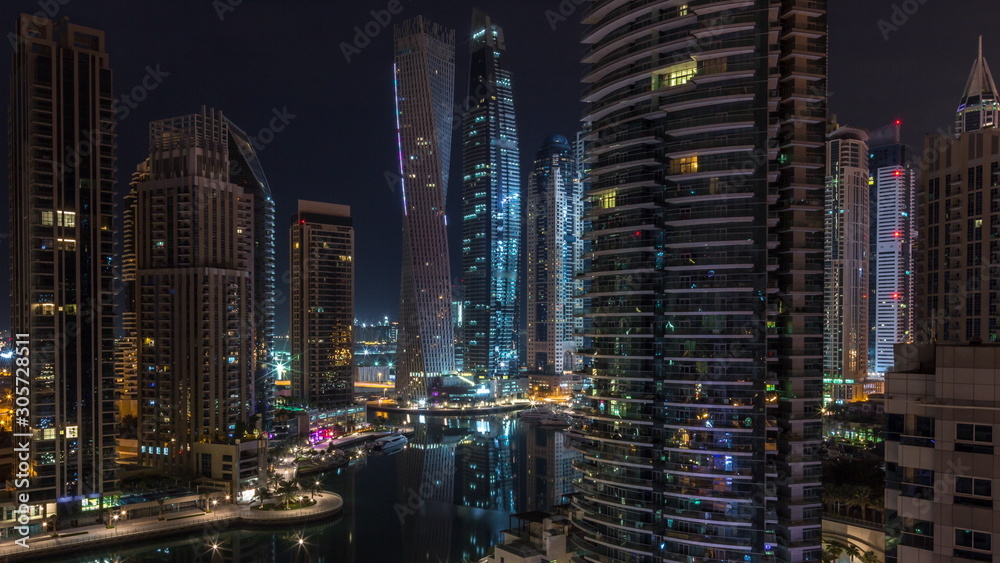 Aerial view of Dubai Marina residential and office skyscrapers with waterfront night timelapse