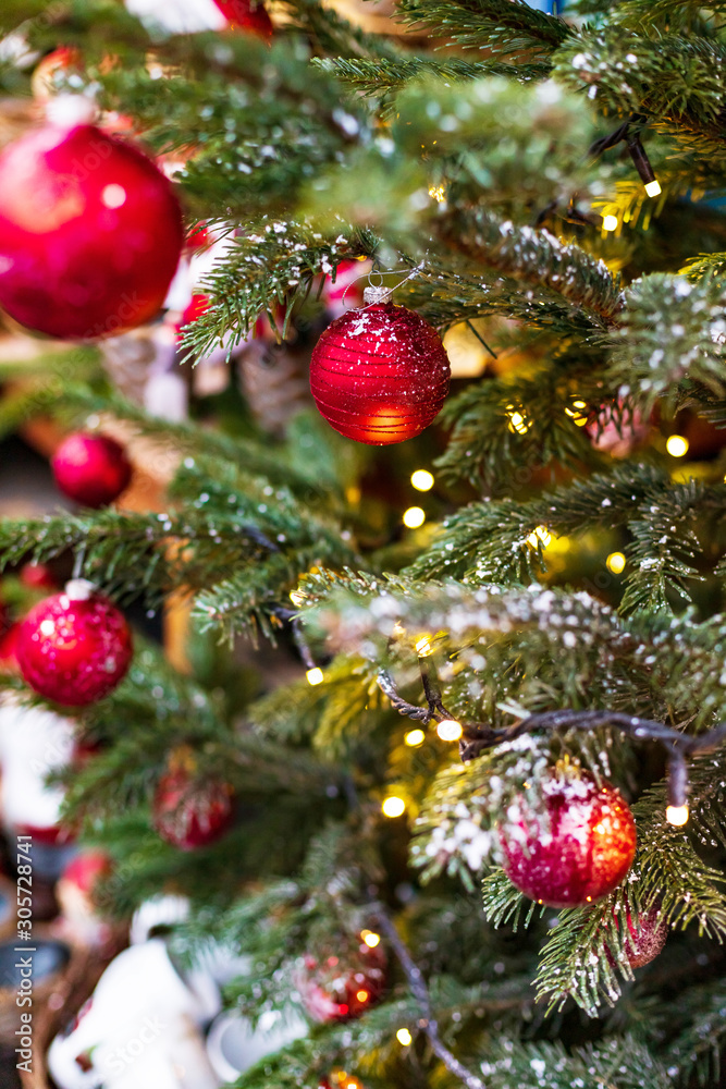 Outdoor decorated Christmas tree with light garland and red balls, selective focus