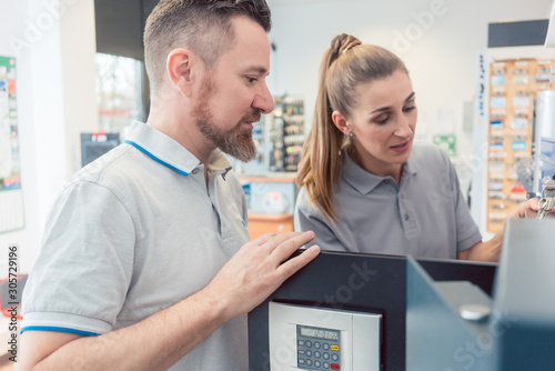 Seller in his shop with customer selling a safe